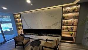 Een moderne woonkamer met een grote televisie, comfortabele zithoek en een decoratieve plank met planten.