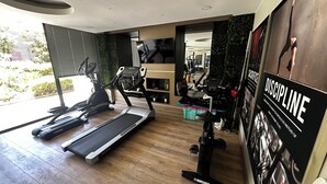 Een moderne sportschool met loopbanden, hometrainers en een muur met motivatieposters.