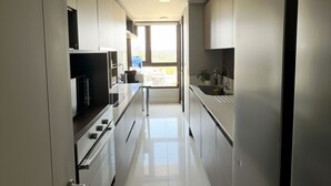 Een moderne keuken met roestvrijstalen apparatuur, een centraal eiland en uitzicht op buiten.