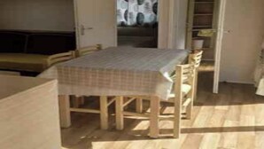 A compact room with a wooden table, chairs, and a bed. - Mobile home 32m2 at the farm (Souvigny-en-Sologne)