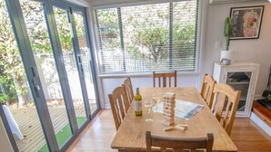 A dining area with a wooden table, chairs, and a glass door leading to a garden. - Bylund Cottage – Historic Charm in the Heart of Albany (MIRA MAR)