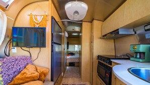 A compact RV kitchen with a stove, microwave, and sink. - Airstream w/ Private Hot Tub (Unit K) - 4 Person Airstream with Private Hot Tub (Williams)