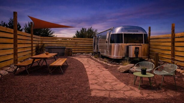 A camper with a kitchen area, a picnic table, and a seating area with chairs. - Airstream w/ Private Hot Tub (Unit K) - 4 Person Airstream with Private Hot Tub (Williams)