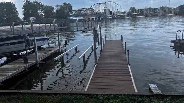 A wooden dock extending into calm water with a roller coaster in the background. - Waterfront 2BR Cottage: Fire Pit, Grill & Dock -Boat Slip Available additional (Monticello)
