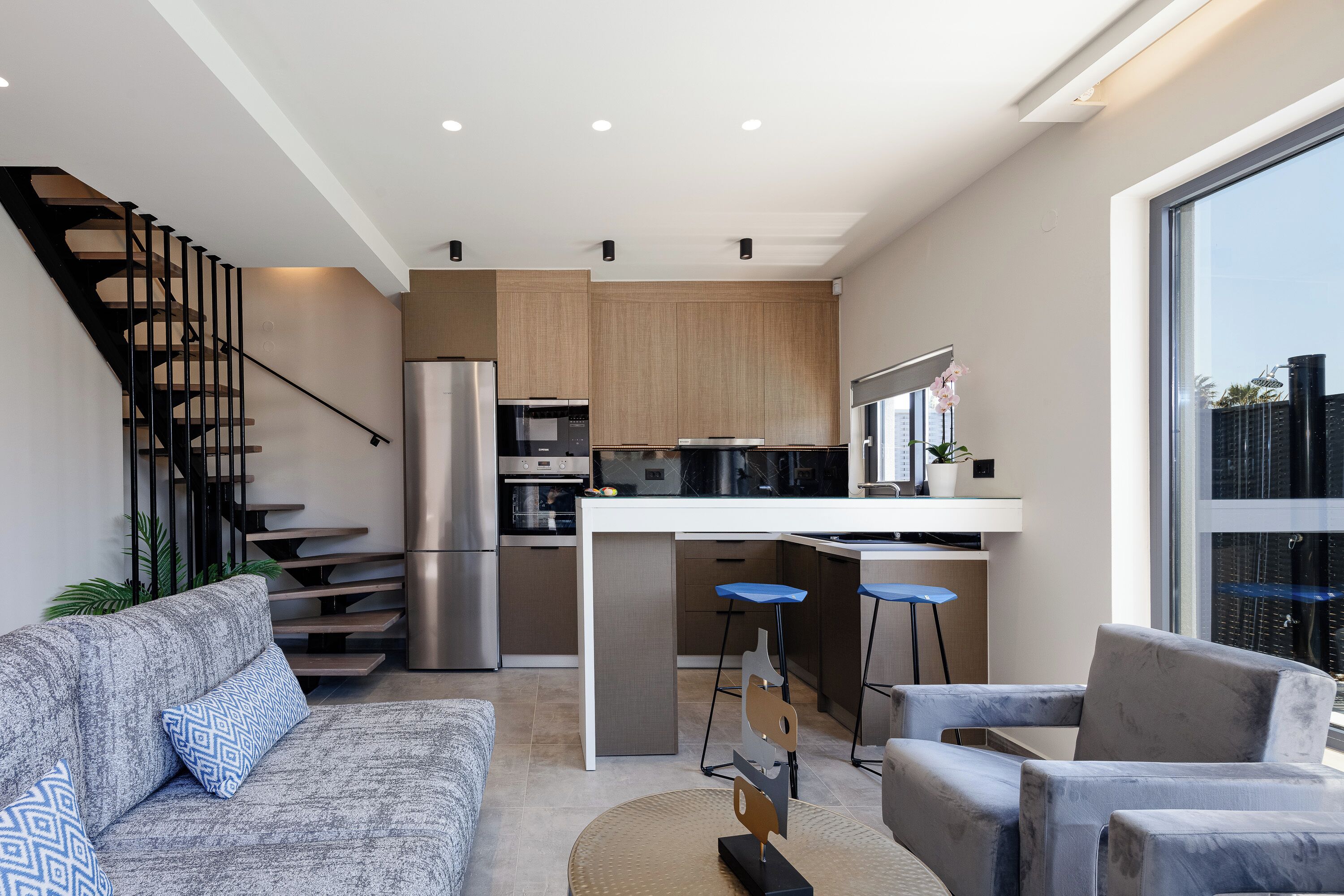 A modern kitchen with a central island, stainless steel appliances, and a bar stool.