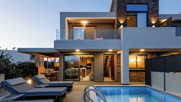 A modern two-story house with a swimming pool, outdoor seating, and a well-lit interior. - VillAgioi (Daratsos)