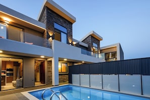 Una piscina al aire libre, sombrillas, sillones reclinables de piscina