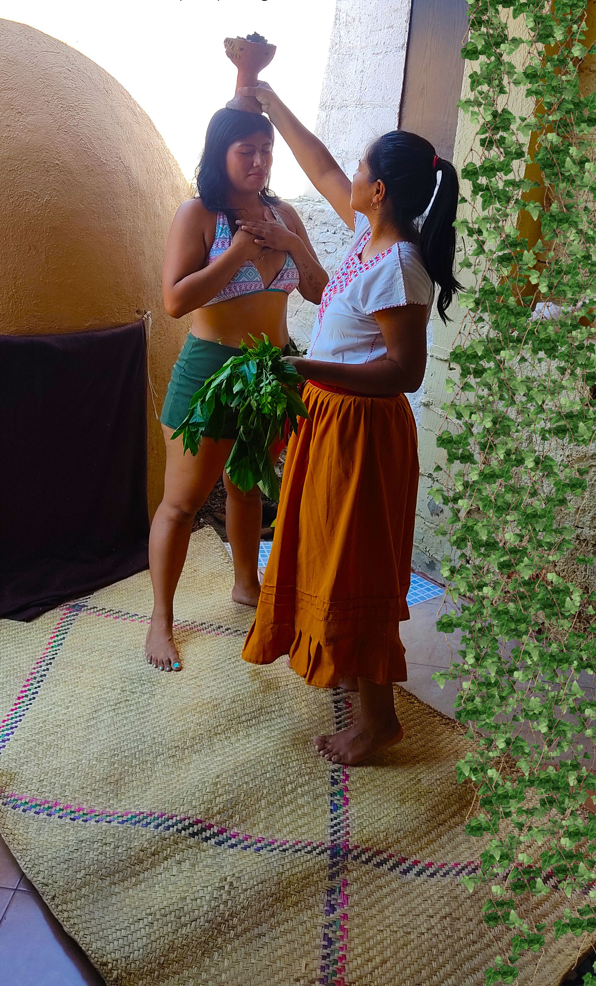 Dos personas de pie sobre un tapete tejido en el interior, con una pared y una planta al fondo.