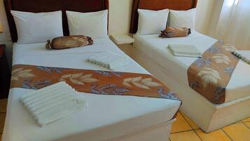 Two single beds with wooden headboards, white bedding, and decorative pillows.