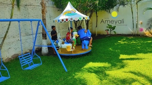 A children's play area with a swing set and a carousel. - Hotel Ameyali Tequesquitengo (Tequesquitengo)