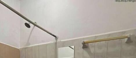 A bathroom with a shower, toilet, sink, and a mirror.