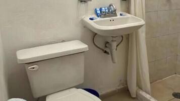 Baño con inodoro, lavabo y cabina de ducha.