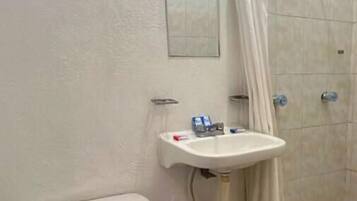 Un baño con inodoro, lavamanos y ducha.
