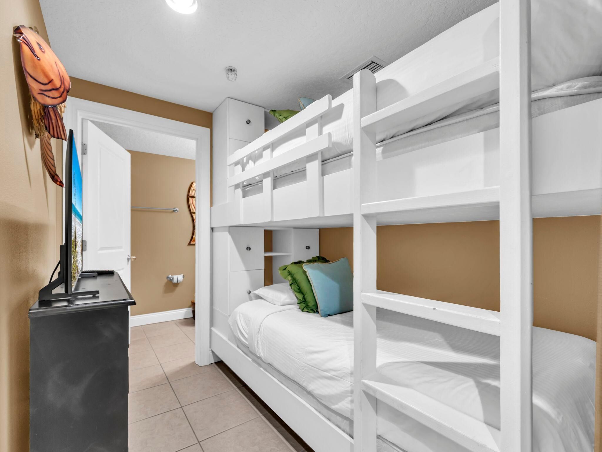 Een slaapkamer met stapelbed, bureau en een deur.