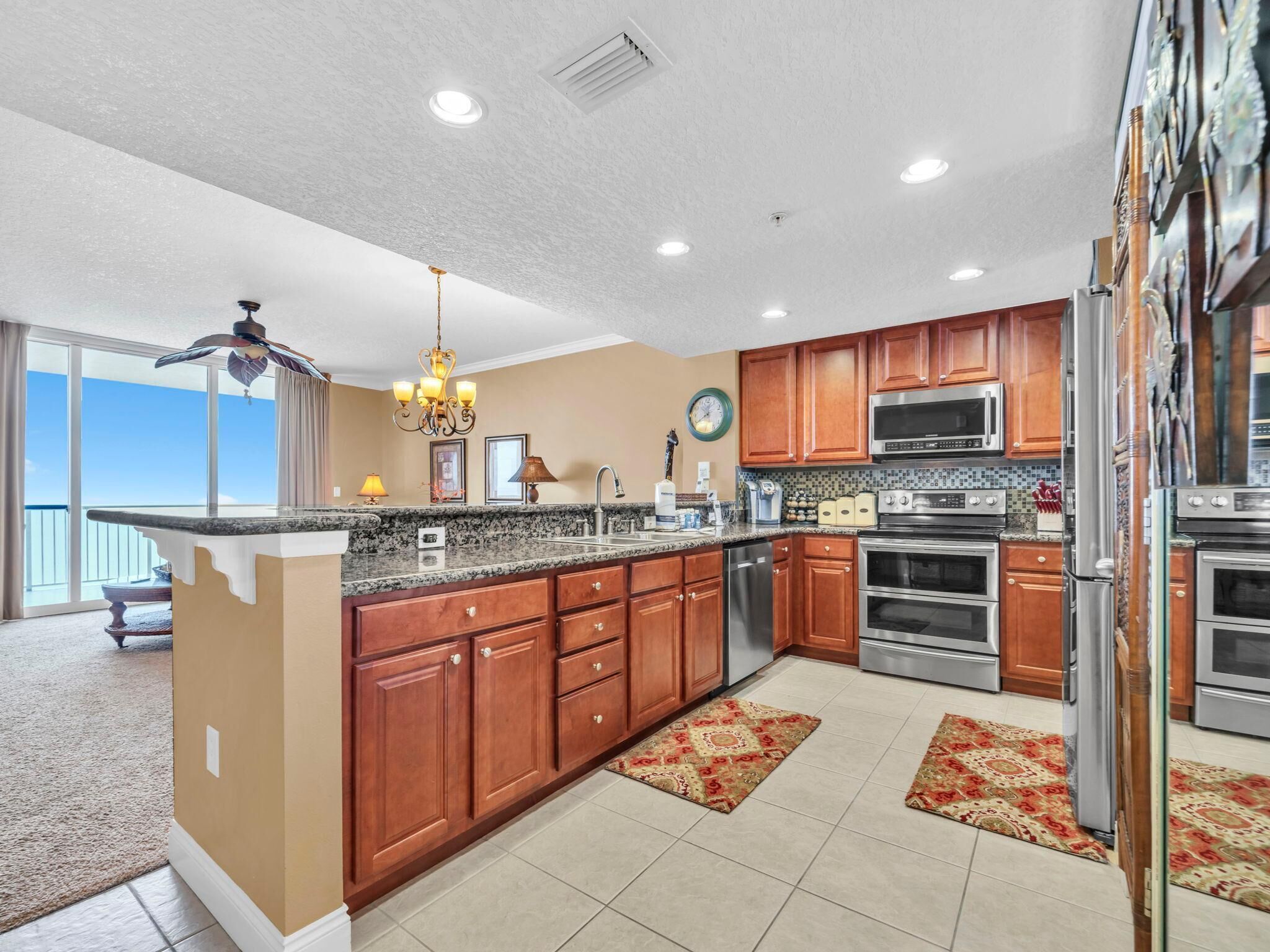 A modern kitchen with wooden cabinets, stainless steel appliances, and a large island with a granite countertop.