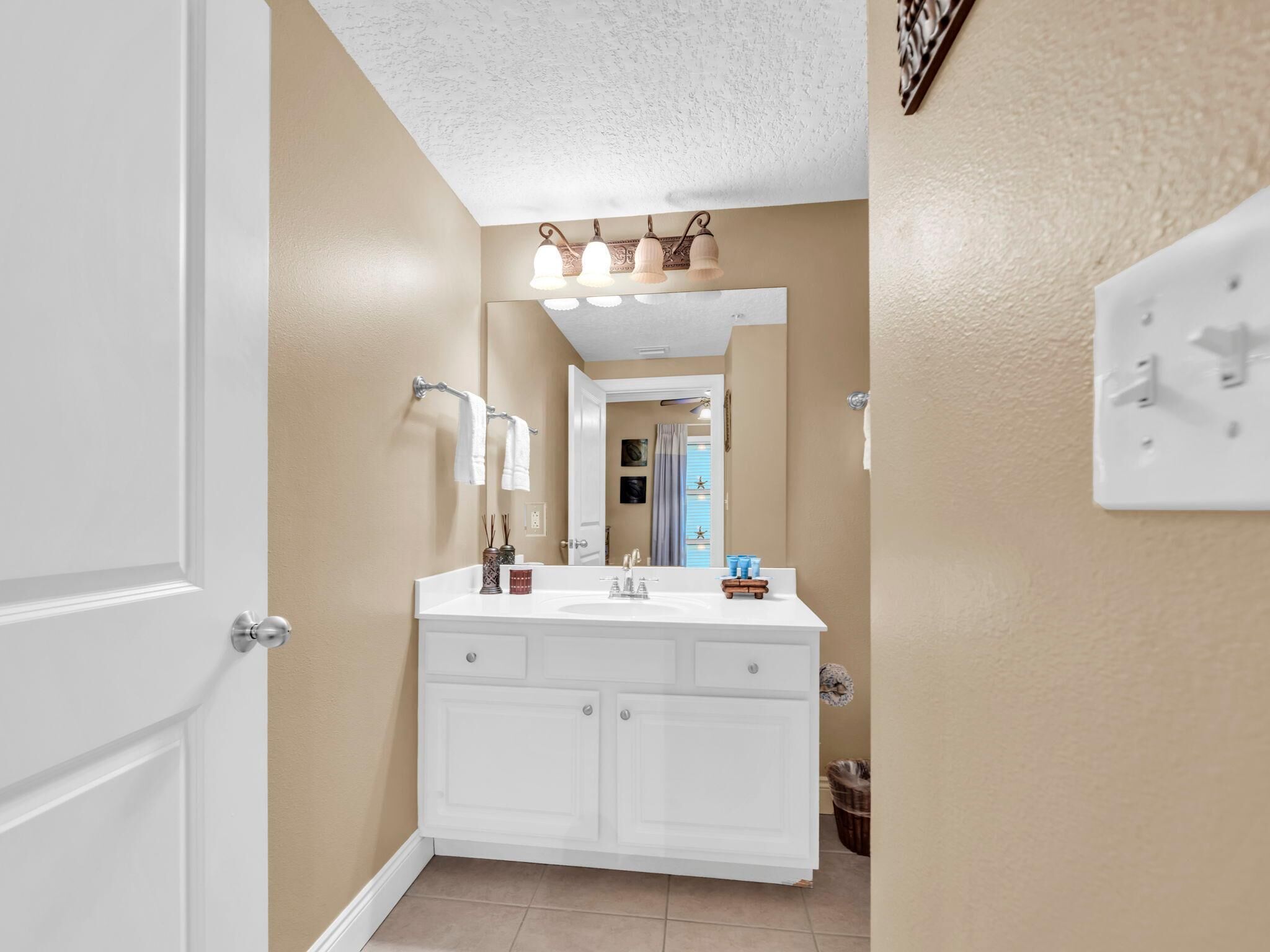 A bathroom with a white vanity, a mirror, and a ceiling light fixture.