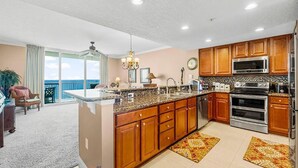 A modern kitchen with wooden cabinets, stainless steel appliances, and a large island.