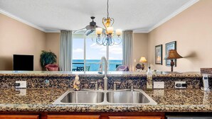 A kitchen with granite countertops, stainless steel sink, and a chandelier.
