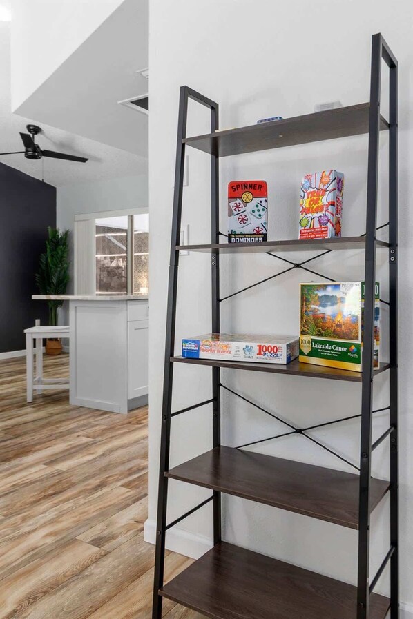 A metal shelf with three board games: Dominoes, 1000 Puzzle, and Lakeside Canoe.