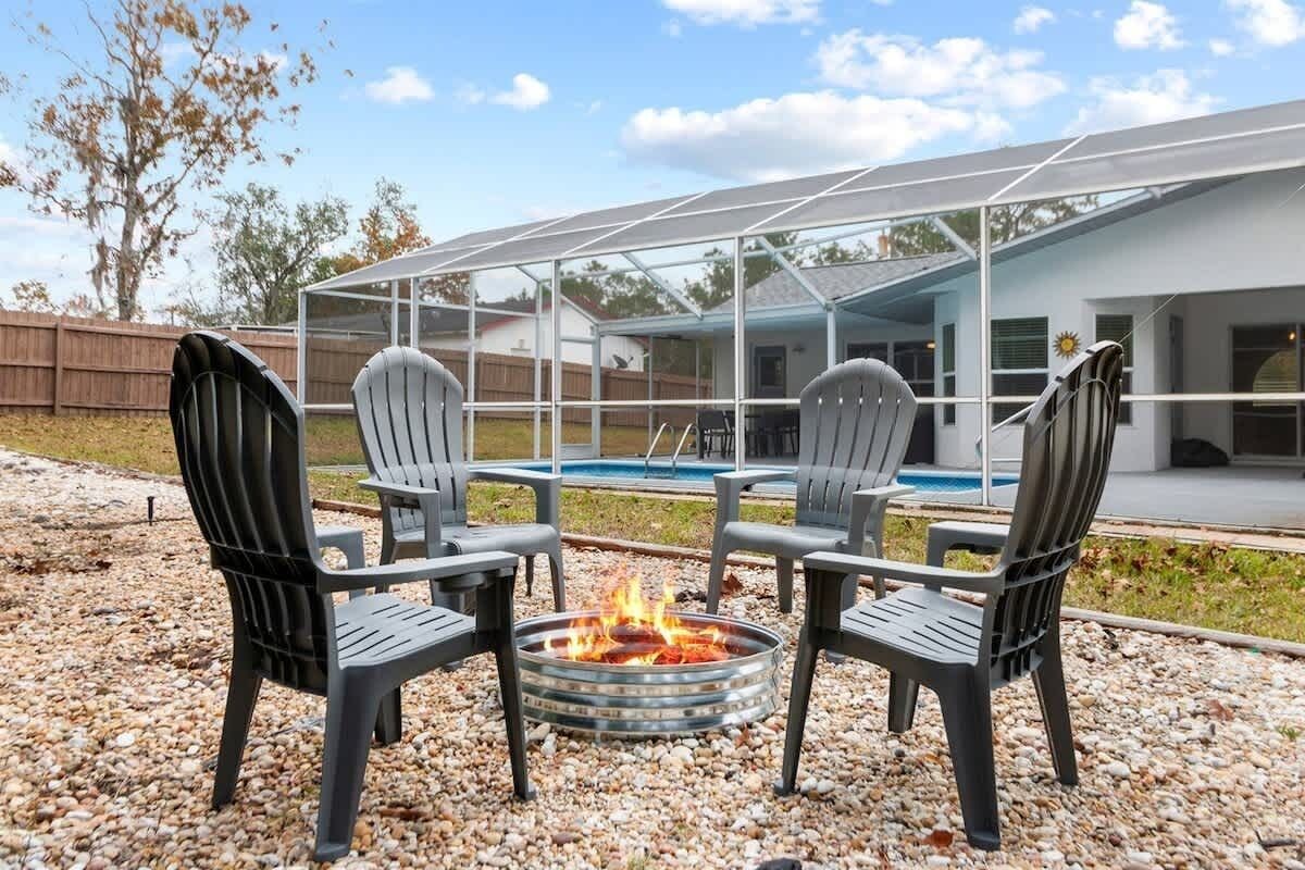 Un espace extérieur aménagé avec deux fauteuils Adirondack et un foyer.