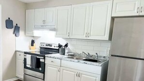 A kitchen with white cabinets, a stainless steel refrigerator, a double oven, and a marble countertop. - Charming Duplex in Zephyrhills! #1 (Zephyrhills)