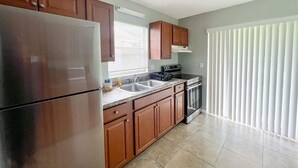 A kitchen with wooden cabinets, a stainless steel refrigerator, a stove, and a dishwasher. - Cozy 2 Bedroom Home, Dade City! #2 (Dade City)