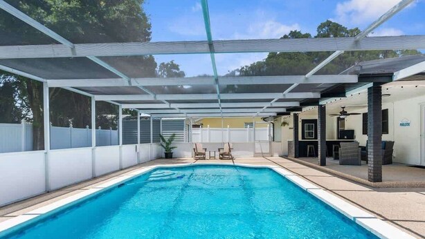 Une piscine couverte avec un espace patio, des chaises et une petite table.