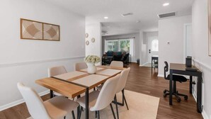 Un espace de salle à manger moderne, avec une table et des chaises en bois, un vase rempli de fleurs et un élément décoratif mural.