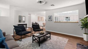 Un salon moderne avec un canapé, deux fauteuils, une table basse et, au fond, un coin repas.