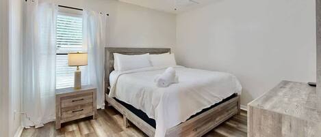 A bedroom with a bed, a nightstand, a lamp, and a ceiling fan.