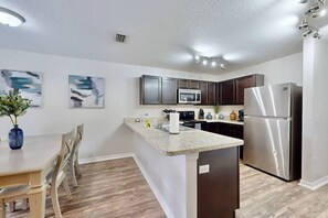 A modern kitchen with a central island, stainless steel appliances, and artwork on the walls.