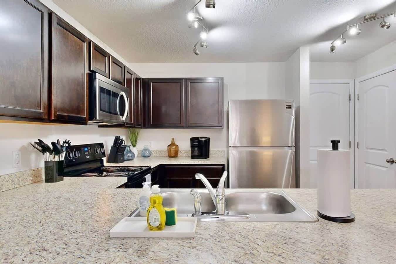 A modern kitchen with dark wooden cabinets, stainless steel appliances, and granite countertops.