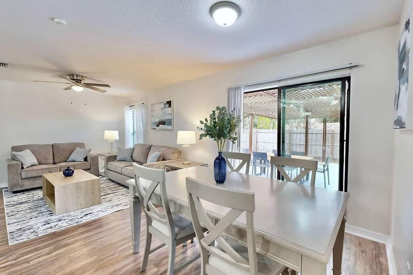 Ein modernes Wohnzimmer mit Essbereich, Deckenventilator und großem Fenster.