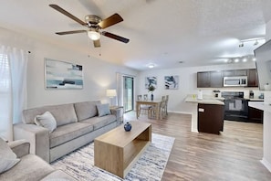 A modern living room with a sofa, coffee table, and a ceiling fan. - Brooksville Retreat! 3 Bed, 2 Bath! (Brooksville)