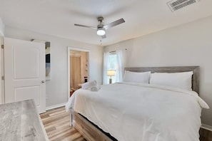A bedroom with a bed, a ceiling fan, a nightstand, and a door. - Brooksville Retreat! 3 Bed, 2 Bath! (Brooksville)