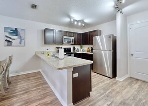 A modern kitchen with a central island, stainless steel appliances, and a dining area with chairs. - Brooksville Retreat! 3 Bed, 2 Bath! (Brooksville)
