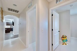 A hallway with white walls and doors leading to a kitchen area. - Brooksville Retreat! 3 Bed, 2 Bath! (Brooksville)