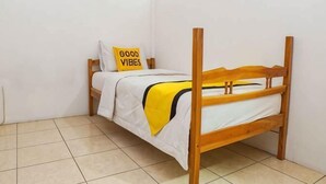 A single bed with a wooden frame, white bedding, and a yellow throw blanket. - Igor Backpacker (Cidadap)