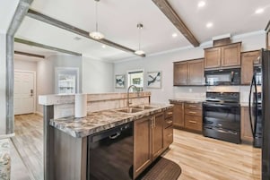 A modern kitchen with a central island, built-in appliances, and wooden cabinetry.