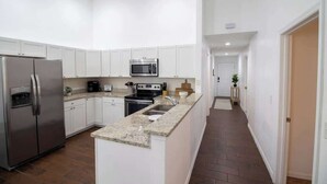 A modern kitchen with white cabinets, stainless steel appliances, and a granite countertop. - Entire Modern Home in Dade City (Dade City)