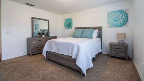 A bedroom with a bed, a dresser, a nightstand, and wall art. - Entire Modern Home in Dade City (Dade City)