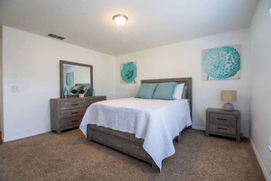 Un dormitorio con cama, cómoda, mesita de noche y decoración en la pared.