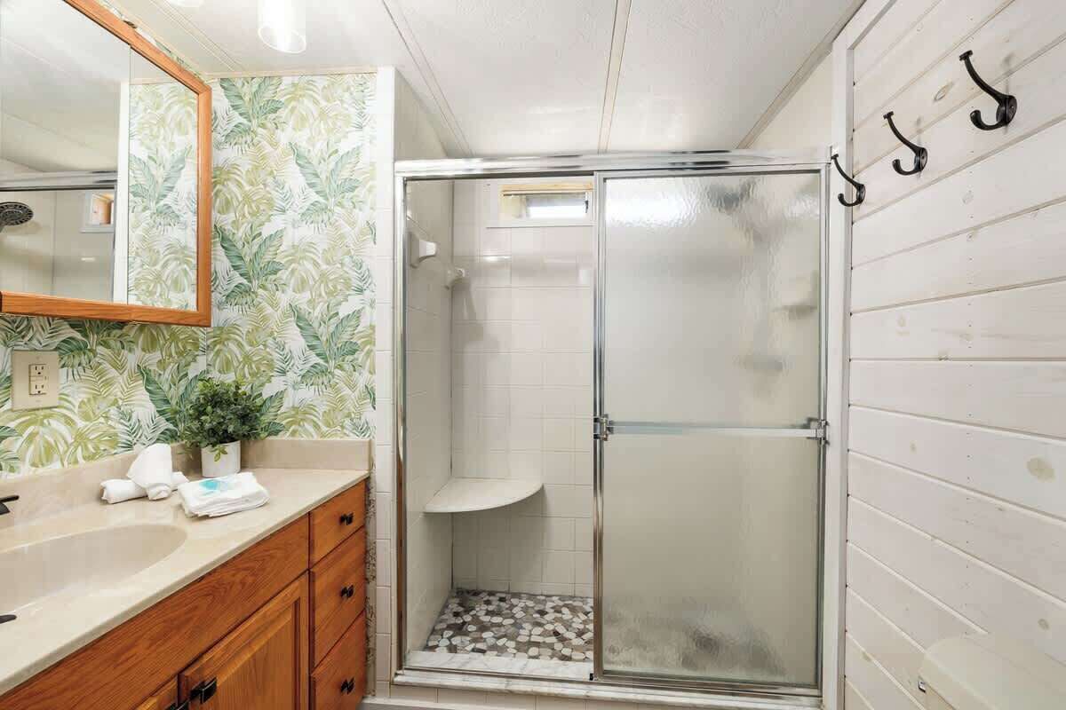A bathroom with a shower, a sink, and a mirror.