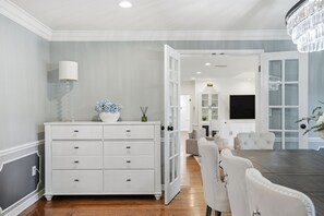 A modern dining area with a white dining table, white upholstered chairs, and a chandelier. - Executive 5 Bedroom Pool Home, Dade City! (Dade City)