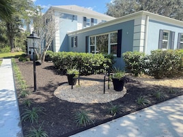 A modern house with a well-maintained garden, including a bench and potted plants.