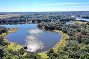 An aerial view of a lake surrounded by dense forest and a river. - Executive 5 Bedroom Pool Home, Dade City! (Dade City)