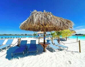 A beach with thatched umbrellas, lounge chairs, and a clear blue sky. - Executive 5 Bedroom Pool Home, Dade City! (Dade City)