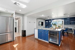 Una cocina moderna con una isla central, armarios blancos y una pared de acento azul.
