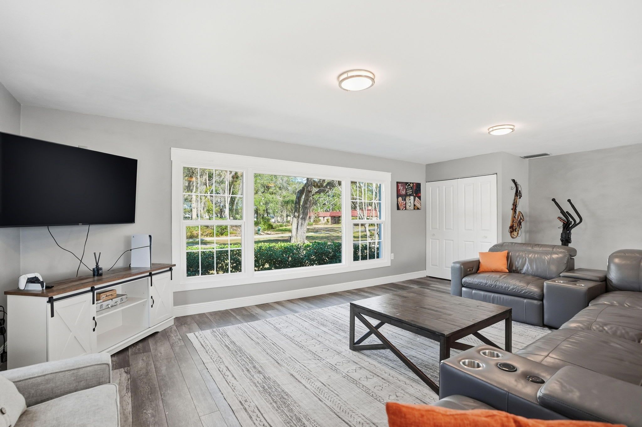 A modern living room with a large window, a flat-screen TV, a leather sofa, and a coffee table.