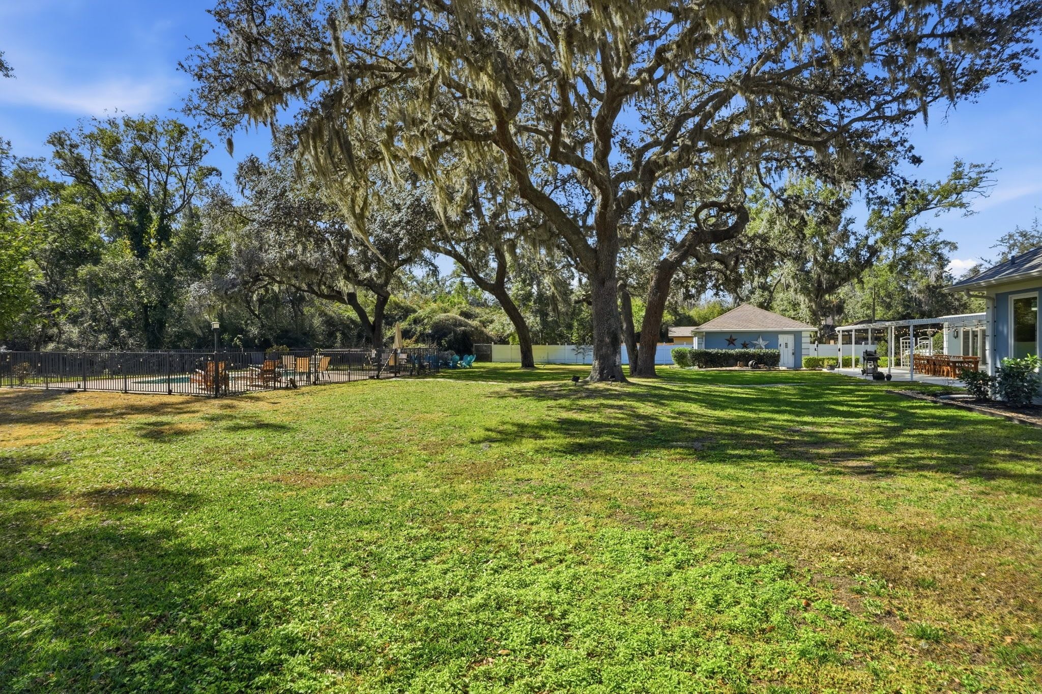 A spacious grassy yard with large trees and a building in the background.